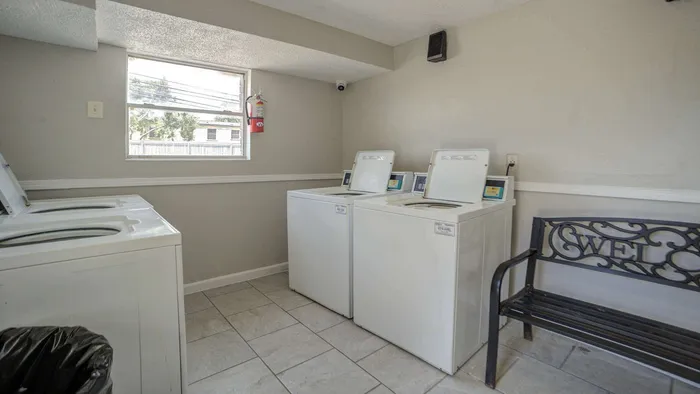 Bright, modern laundry room with washers, a stylish bench, and ample natural light.