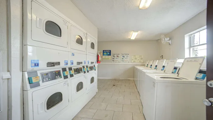 Bright, modern laundry room with stacked washer-dryer units and ample space, equipped for convenient apartment living.