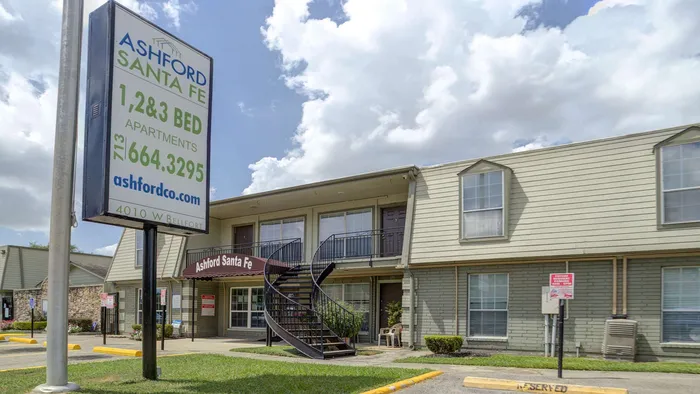Inviting Ashford Santa Fe apartment complex under a bright sky, featuring stylish architecture with inviting outdoor staircase access.