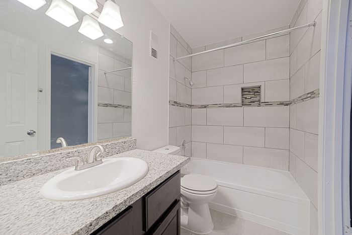 Modern bathroom featuring sleek granite countertop, elegant tile shower, and stylish lighting fixtures.
