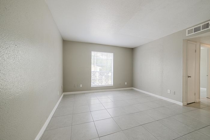Bright and spacious room with elegant tiled flooring and soft gray walls, perfect for a modern living area or cozy bedroom.