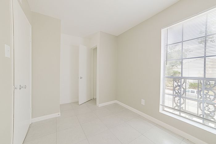 Bright and airy room with elegant tiled floor and a large window, offering abundant natural light and a serene ambiance.