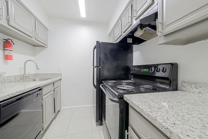 Chic modern kitchen with sleek black appliances, elegant granite countertops, and ample cabinetry.