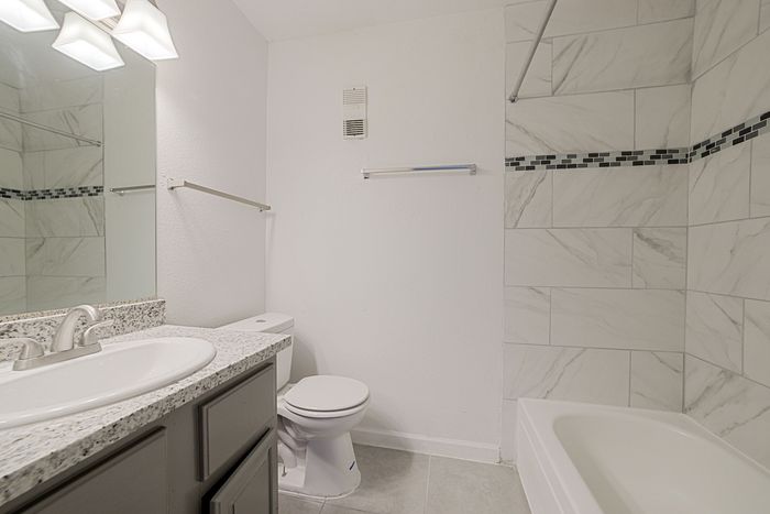 Elegant bathroom with modern fixtures, featuring a sleek marble-inspired tile design and contemporary vanity.