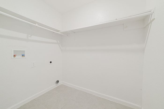 Pristine, spacious laundry room with sleek white walls and ample shelving, perfect for organizing and efficiency.