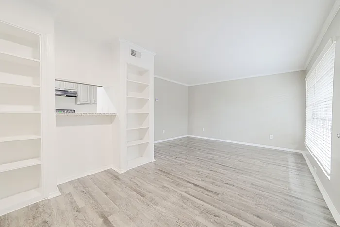 Bright and airy apartment with open-concept layout, featuring elegant hardwood floors and built-in shelving, perfect for stylish living.