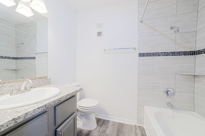 Bright, modern bathroom with sleek granite countertop, elegant fixtures, and sophisticated tiled bathtub design.