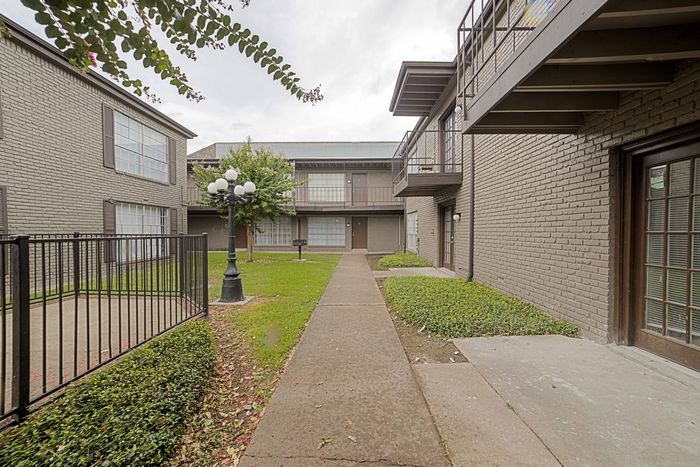 Charming apartment courtyard with modern architecture, featuring lush greenery and stylish lighting fixtures.