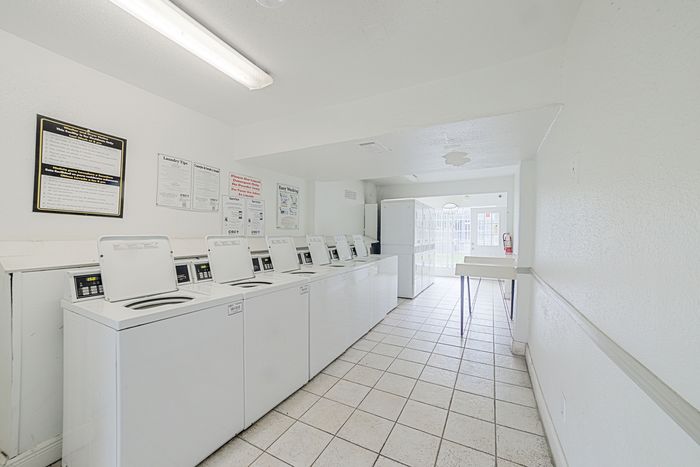 Bright and clean laundry room with multiple washing machines, ample space, and natural light.