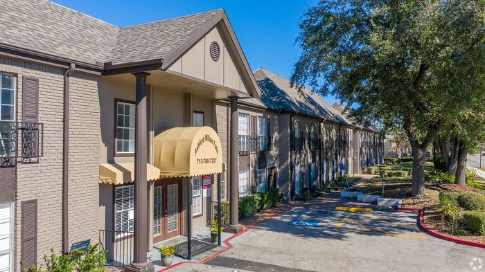 Charming apartment building with classic architecture, featuring a welcoming entrance with columns and lush green surroundings.