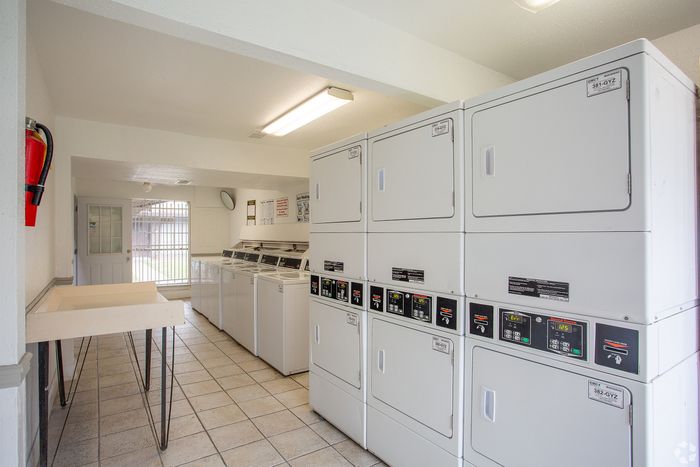 Bright and clean community laundry room featuring multiple washers and dryers, ideal for convenient living.