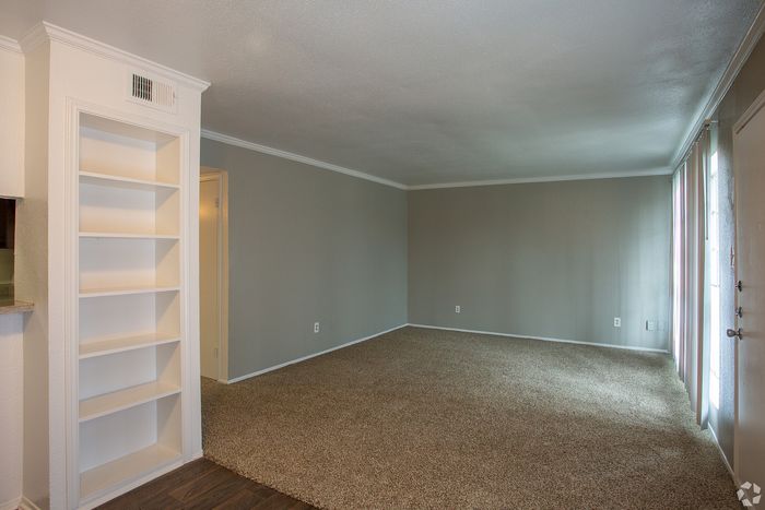 Inviting living room with plush carpet, built-in shelving, and abundant natural light.