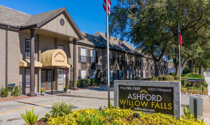 Charming exterior of Ashford Willow Falls apartment community, featuring elegant brick architecture, lush landscaping, and welcoming entrance.