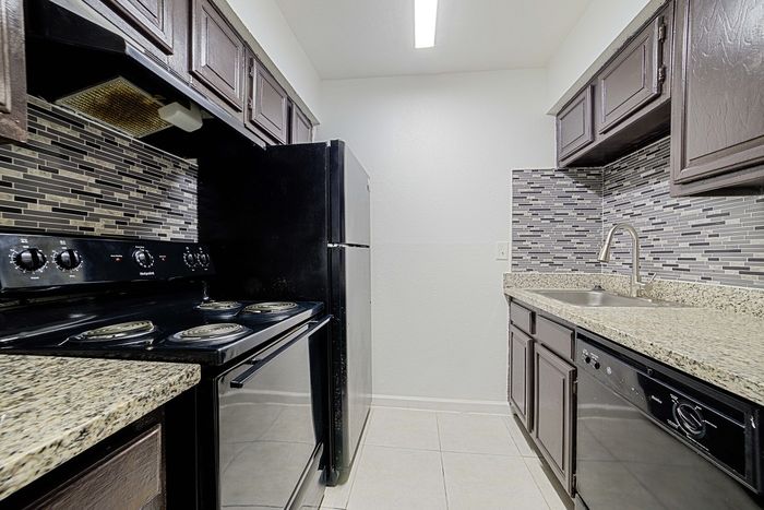 Sleek modern kitchen with stylish dark cabinetry, elegant granite countertops, and contemporary mosaic backsplash.