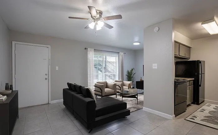 Inviting open-plan living area featuring modern furniture, natural light, and a sleek kitchen in a stylish apartment.