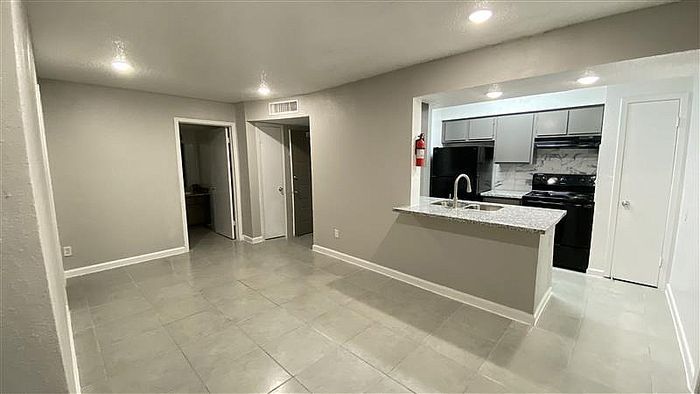 Modern open-plan apartment featuring sleek kitchen with marble backsplash, inviting living space, and contemporary lighting.