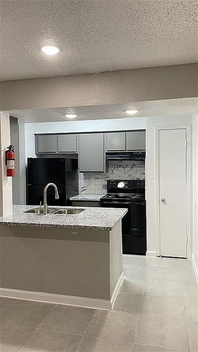 Modern kitchen with sleek gray cabinetry, granite countertops, and stylish tiled backsplash.
