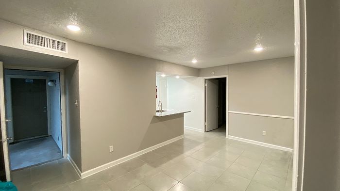 Inviting open-plan apartment featuring a sleek breakfast bar with modern lighting and neutral tiled flooring.
