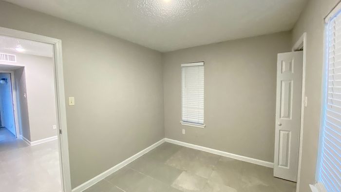 Cozy, freshly painted small room with sleek tiled flooring and abundant natural light from a window, ideal for a tranquil retreat.