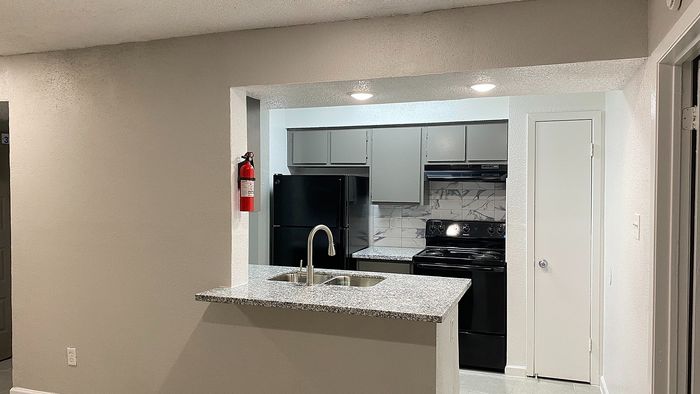 Modern kitchen featuring sleek granite countertops, elegant backsplash, and recessed lighting for a sophisticated look.