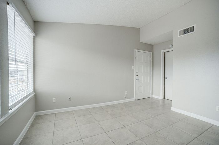 Bright and spacious room featuring large windows, sleek tile flooring, and a modern interior with white walls, perfect for customization.