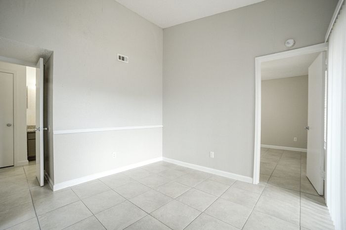 Bright, airy room with sleek tile flooring and neutral walls, offering versatile design potential in a modern apartment.