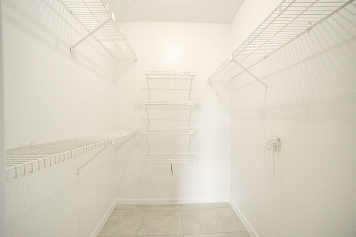 Spacious walk-in closet with sleek wire shelving and modern tiled flooring, perfect for organized living.