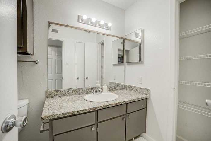 Modern bathroom with elegant granite countertop, sleek cabinets, and spacious shelving.