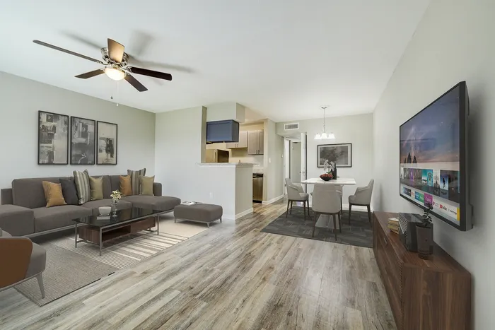 Modern open-concept living room with cozy sectional sofa, large flat-screen TV, and elegant dining area adjacent to a stylish kitchen.