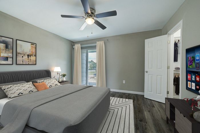 Elegant bedroom with a cozy ambiance, featuring dark wood flooring, a plush bed with stylish pillows, modern ceiling fan, and a private balcony view.