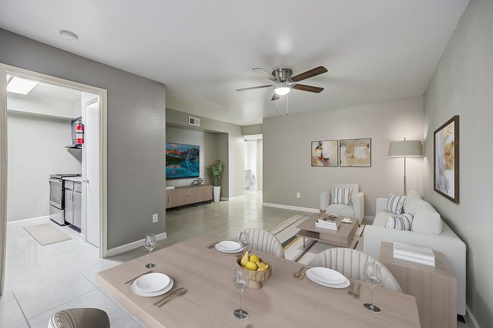 Contemporary living space featuring an elegant dining area, cozy lounge with modern art, and a sleek kitchen entrance, perfect for stylish urban living.