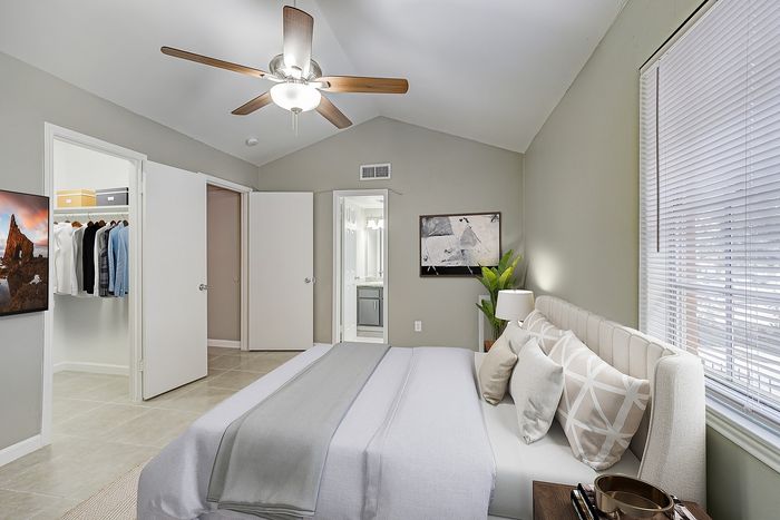 Elegant bedroom with soft lighting, featuring a cozy bed, stylish fan, and ample closet space, creating a serene and inviting atmosphere.