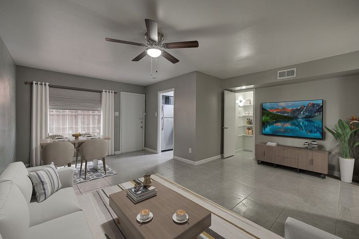 Contemporary living room with stylish decor, open dining area, modern ceiling fan, and sleek wall-mounted TV, emphasizing elegance and comfort.