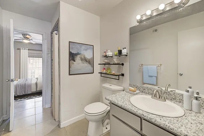 Elegant bathroom with granite countertop, sleek shelving, and soft ambient lighting, offering a glimpse into a cozy bedroom.