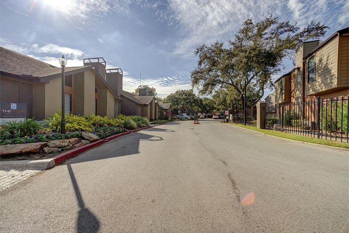 Inviting entrance to The Cove Leasing Center, surrounded by lush greenery and vibrant landscaping under a beautiful blue sky.