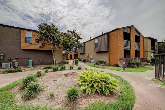 Charming apartment complex with modern architecture, lush greenery, and inviting pathways under a serene sky.