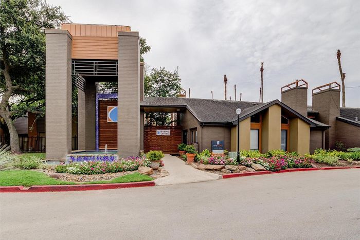 Inviting apartment complex entrance featuring modern architecture, lush landscaping, and a welcoming leasing center.