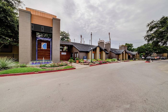 Charming apartment complex entrance highlighted by modern architectural design, vibrant greenery, and welcoming pathway.