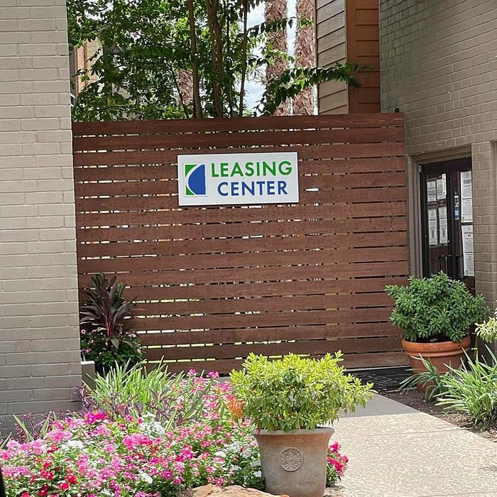 Inviting leasing center entrance adorned with colorful flowers and lush greenery, offering a warm welcome.