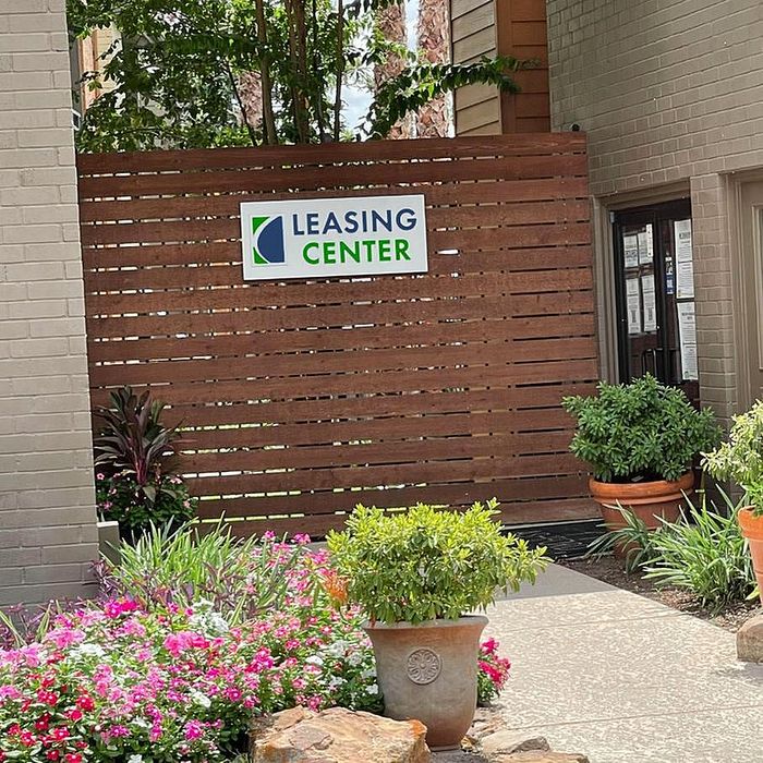 Inviting leasing center entrance surrounded by vibrant flowers and lush greenery, promising a welcoming atmosphere.