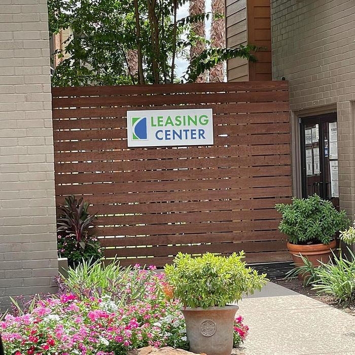 Inviting leasing center entrance adorned with vibrant flowers and lush greenery, offering a welcoming atmosphere.