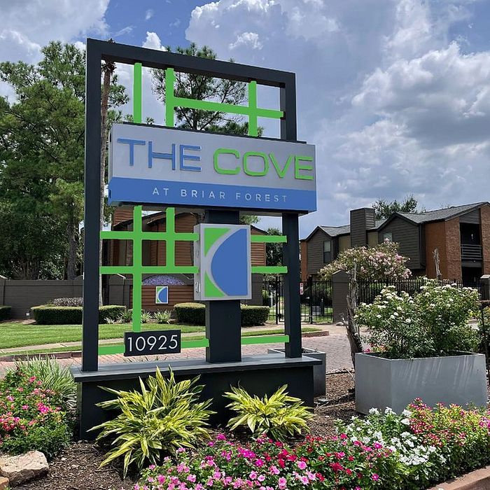 Inviting entrance sign of The Cove at Briar Forest, set amidst lush greenery and vibrant flowerbeds, reflecting a welcoming community vibe.