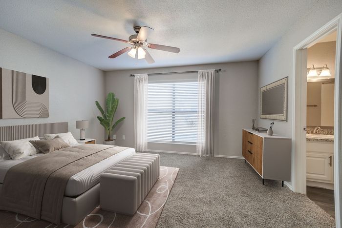Inviting bedroom with modern decor, featuring a cozy bed, elegant ceiling fan, and adjacent en-suite bathroom.