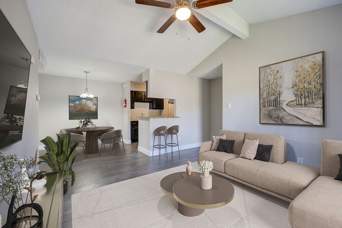 Modern living area with elegant beige sofas, artful wall paintings, and open kitchen view featuring stylish bar stools.