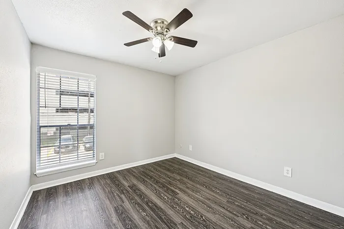 Bright and inviting room with a sleek ceiling fan and elegant laminate wood flooring, perfect for a cozy bedroom setup.
