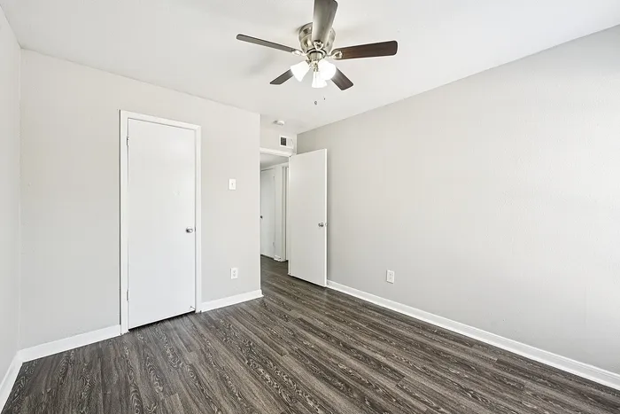Bright bedroom with elegant wood flooring and a modern ceiling fan, perfect for a cozy and inviting space.
