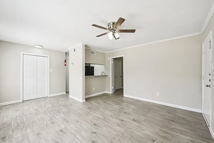 Inviting open-plan living area with light wood flooring, elegant ceiling fan, and adjacent kitchen passthrough.