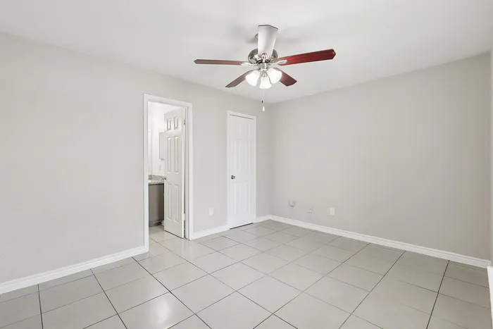 Bright, spacious room with modern ceiling fan and sleek tiled floors, ideal for versatile living.