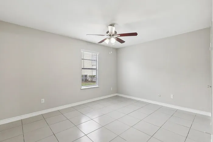 Bright, spacious room with modern ceiling fan and elegant tile flooring, perfect for versatile interior design.
