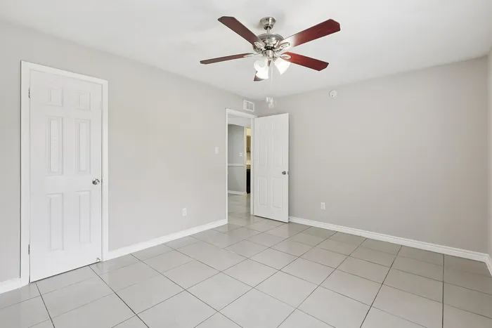 Bright, newly renovated room with sleek tiled flooring and a modern ceiling fan, offering a fresh canvas for stylish living.